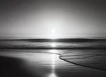 Black and white minimalist beach scene at sunset with gentle waves and a soft horizon, symbolizing calm and introspection. The serene shoreline evokes a sense of balance, peace, and mindfulness, perfect for a blog about starting a meditation practice for holistic health.