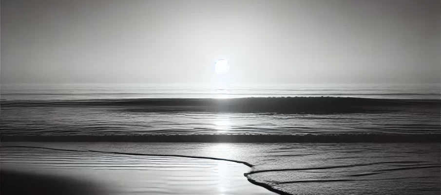 Black and white minimalist beach scene at sunset with gentle waves and a soft horizon, symbolizing calm and introspection. The serene shoreline evokes a sense of balance, peace, and mindfulness, perfect for a blog about starting a meditation practice for holistic health.